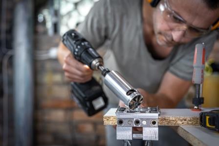 The carpenter works with a professional precision drilling tool.
